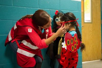 Red Cross volunteer Lilliana Matos helps Ferndanda Velasco with her mask, as sister Maria Velasco looks on. (Photo by Jason Colston/American Red Cross)